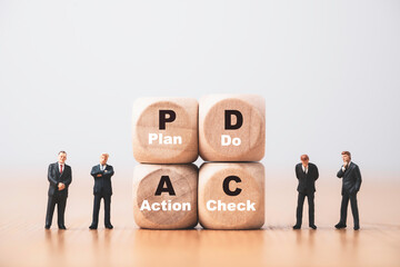 Four businessmen standing and thinking with wooden cube which print screen PDCS or Plan Do Check Action concept.