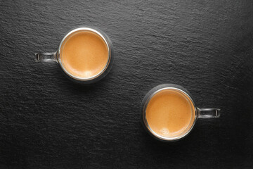 two cups of coffee on a black background flat lay. Two glass coffee cups flat lay. Coffee on black slate top view. Coffee drink in a double glass.