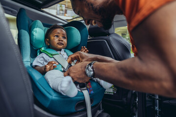 Father fastening seat belt of son in car
