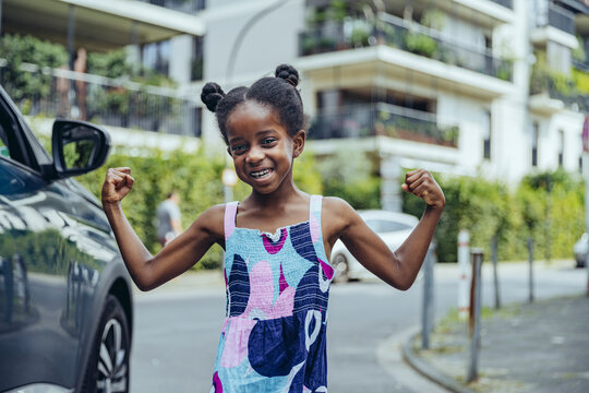 Smiling girl flexing muscles on road