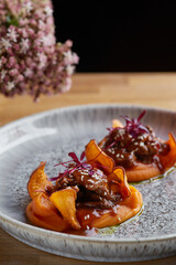 beef with sauce and sweet potato on a restaurant table with a flowers close up. restaurant dinner with dark background