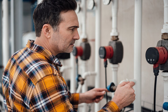 Employee examining machinery in greenhouse