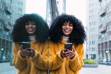 Smiling woman using smart phone in city