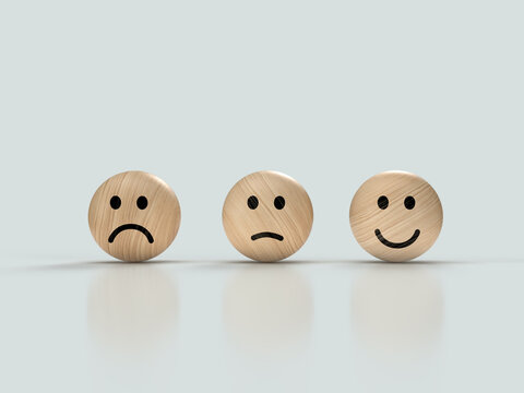 Three wooden faces with emotions: smile - happy, serious - neutral and angry - displeased, concept picture