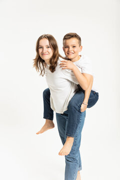 Sister giving brother piggyback ride in studio