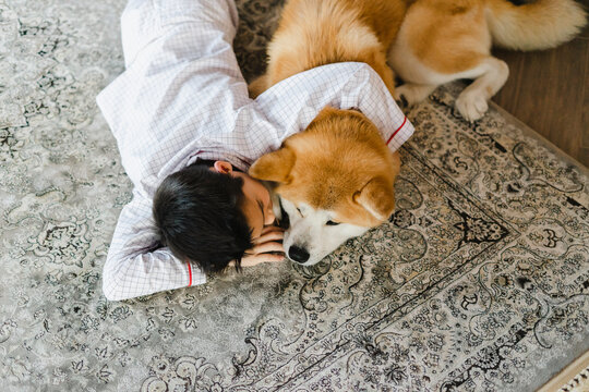 Boy with pet dog on carpet at home