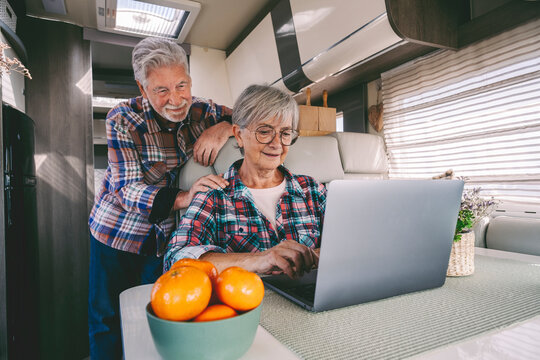 Smiling senior woman using laptop by man in camper van