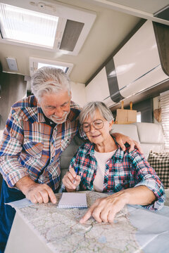 Smiling senior couple discussing over guide map in camper van