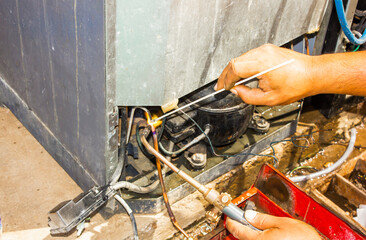 technician repair refrigerator by welding copper pipe and vacuum at maintenance shop