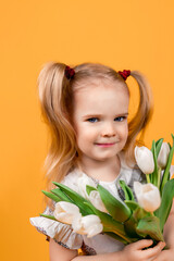 a little girl in a beautiful dress with curly tails on a plain yellow background