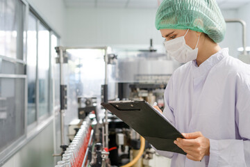 Quality control engineers work in the production and bottling facility for fruit juice or medicine....