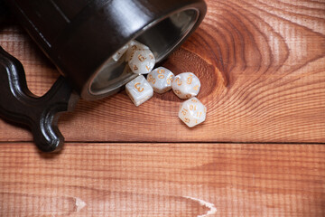 Set of role playing white dices are falling from wooden  stylized beer mug for playing role-playing game on wooden background, top view with place for text, close up