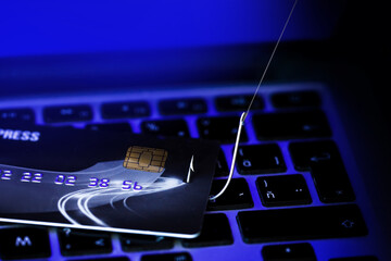 Phishing Credit Cards - Piles of credit cards with fish hook on computer keyboard. Dark Background.
