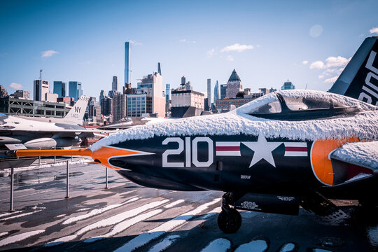 View of a F-9 Cougar fighter jet on the flight deck of USS Intrepid Sea, Air and Space Museum in front of the Manhattan skyline, New York, NY, USA