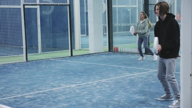 Teenage boy and girl playing padel in court together. High quality 4k footage