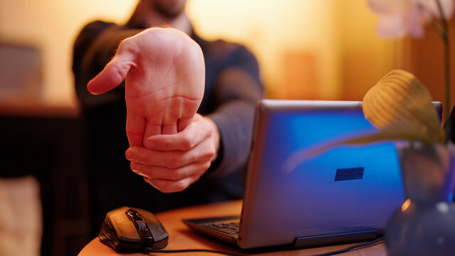 Headless Person Behind The Laptop Computer Stretch Wrist Towards The Camera Work At Home