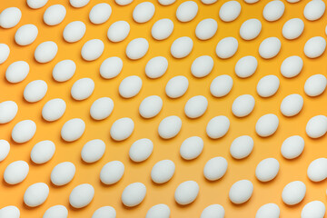 Pattern from white chicken eggs on yellow background top view. Creative food minimalistic background.