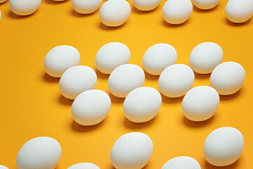 White chicken eggs on yellow background top view. Creative food minimalistic background.