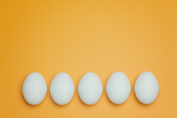 Five white chicken eggs on yellow background top view. Creative food minimalistic background.