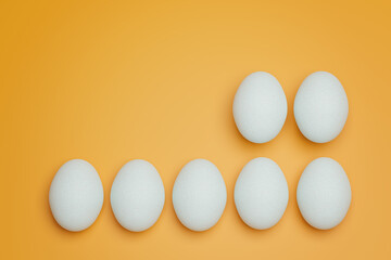 Seven white chicken eggs on yellow background top view. Creative food minimalistic background.