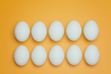 Ten white chicken eggs on yellow background top view. Creative food minimalistic background.