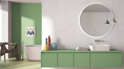 Cozy minimalist bathroom in green pastel tones, washbasin with mirror, bathtub, tiles and concrete walls, armchair, colored vases and decors, interior design project concept idea