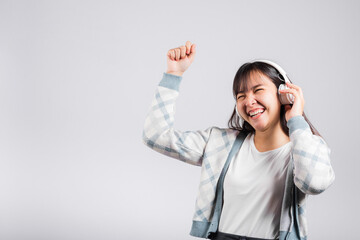 Woman excited smiling listening to music radio in bluetooth headphones and dancing with smartphone...