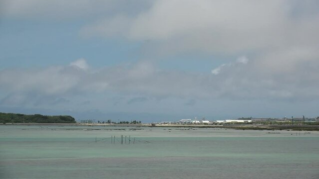 TOMIGUSUKU, OKINAWA, JAPAN - AUGUST 2021 : View of Senaga island beach (Ocean or sea) and airplane in daytime. Clear blue summer sky and clouds. Holiday, vacation and resort concept video.