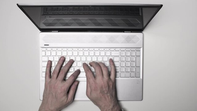 hands typing on laptop with white background, slow zoom out.