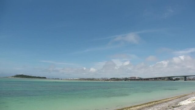 TOMIGUSUKU, OKINAWA, JAPAN - AUGUST 2021 : View of Senaga island and beach (Ocean or sea) in daytime. Clear blue summer sky and clouds. Holiday, vacation and resort concept video. Time lapse shot.
