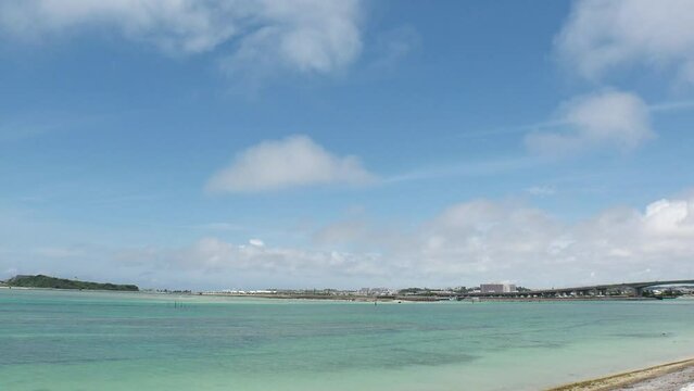 TOMIGUSUKU, OKINAWA, JAPAN - AUGUST 2021 : View of Senaga island and beach (Ocean or sea) in daytime. Clear blue summer sky and clouds. Holiday, vacation and resort concept video. Time lapse shot.