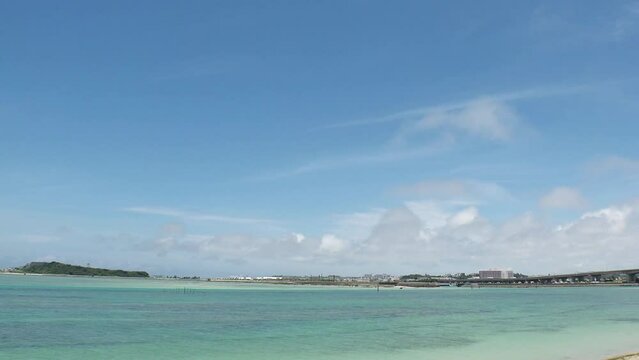TOMIGUSUKU, OKINAWA, JAPAN - AUGUST 2021 : View of Senaga island and beach (Ocean or sea) in daytime. Clear blue summer sky and clouds. Holiday, vacation and resort concept video. Time lapse shot.
