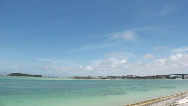 TOMIGUSUKU, OKINAWA, JAPAN - AUGUST 2021 : View of Senaga island and beach (Ocean or sea) in daytime. Clear blue summer sky and clouds. Holiday, vacation and resort concept video. Time lapse shot.
