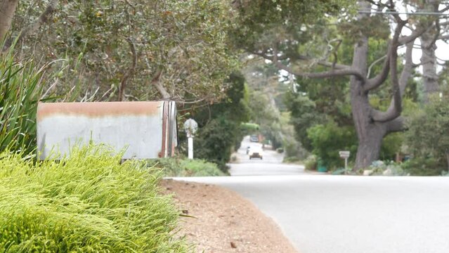 Typical generic suburban street, residential district with detached single-family houses, Carmel city road, Monterey, California USA. Trees grenery in neighborhood suburb. Dropbox, mailbox or postbox.
