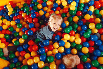Fototapeta na wymiar Happy Children Playing in a Ball Pit Pool in Amusement Park. Boys Playing and Having Fun at Children Play Centre
