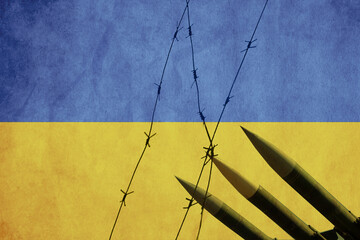 Flag of Ukraine painted on a concrete wall with wire fence and missiles. Relationship between...
