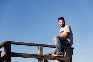 Fototapeta premium man looking at camera sitting on a wooden railing