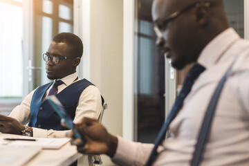 Two dark-skinned partners of an African American businessman in a meeting work on a laptop in the office. Affordable private courses and distance learning. New opportunities online