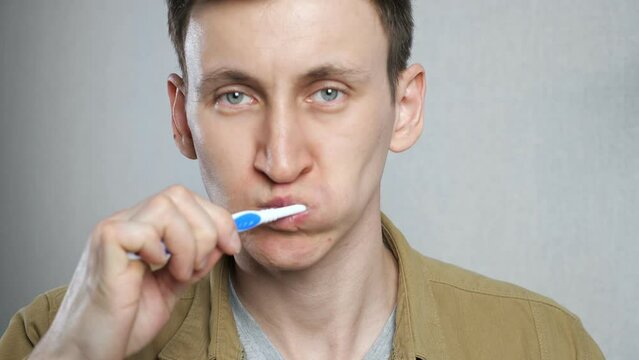 Close up head shot young man brushing teeth in bathroom. Person doing morning oral mouth hygiene daily procedure, toothcare