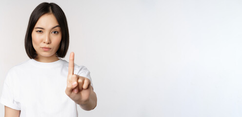 Image of asian girl showing stop, prohibit smth, extend one arm to show forbidding, taboo gesture,...