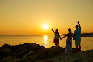 A happy family watching a beautiful sunset on the sea. The concept of a family holiday by the sea