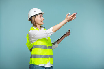 Professional engineer. A woman in a hardhat and bright jelly is using a tablet, on a blue background. Copy paste.