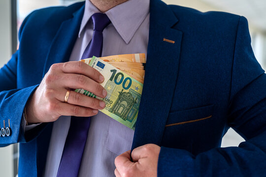 Businessman putting euro bills into pocket hit jacket