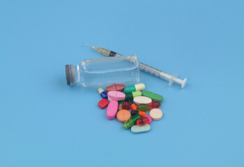 Drugs, pills and syringe with vaccine on blue background. Pharmacy, healthcare and medical concept.	