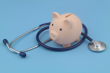 Piggy bank and stethoscope blue background. Save money and cost of medicine concept.	