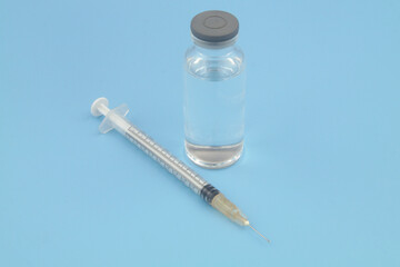 Vaccine bottle and syringe on blue background. 
