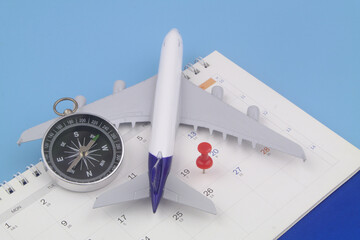 Airplane with compass and push pin on calendar. 