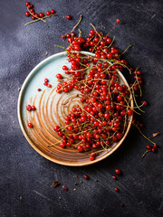 Juicy fresh red currant berries on a plate on dark background