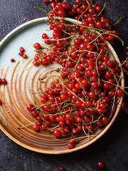 Juicy fresh red currant berries on a plate on dark background