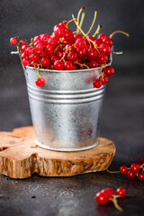 Juicy fresh red currant berries in a bucket with water splash on a dark background